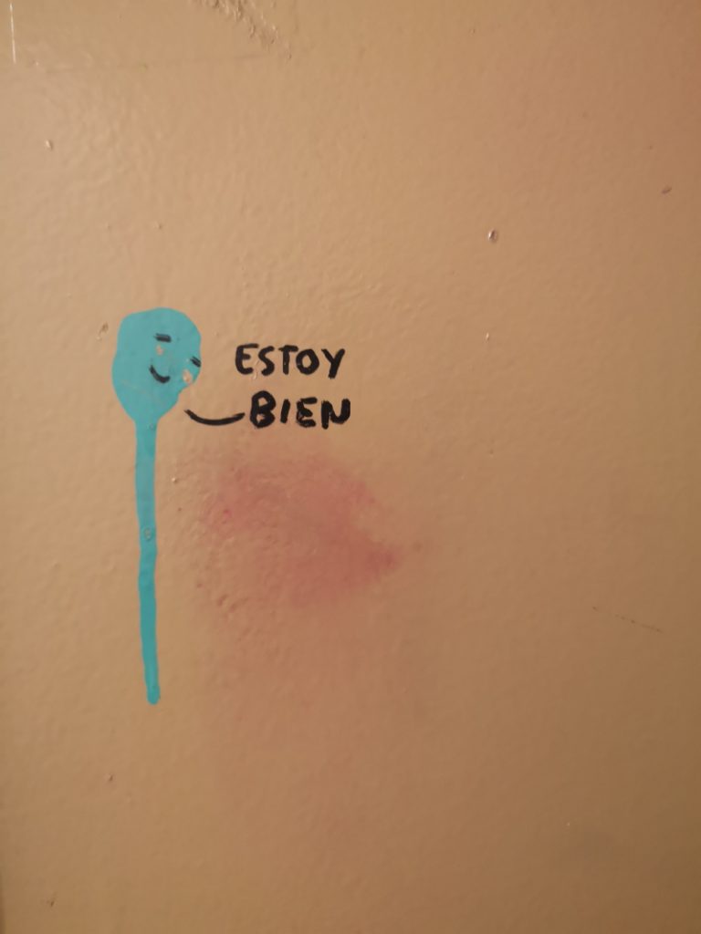 Persona garabateada en una pared que dice “Estoy bien” / Dibuix d’una persona a una paret que diu “Estic bé”